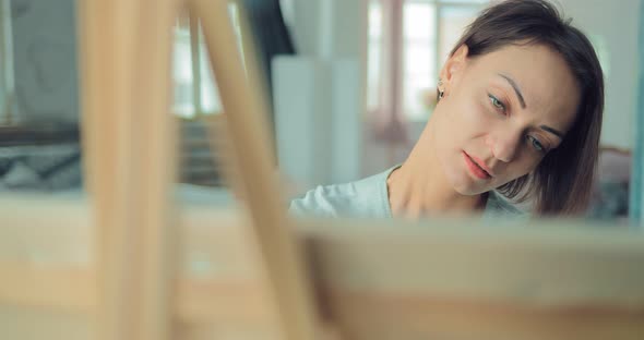 Beautiful Young Woman Enthusiastically Working at the Easel alt