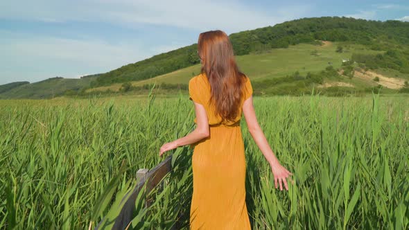 Woman in a long dress, walking in a reed field alt