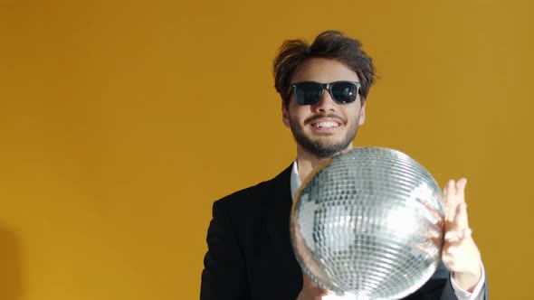 Slow Motion Portrait of Cheerful Mixed Race Man Holding Glitterball and Dancing alt