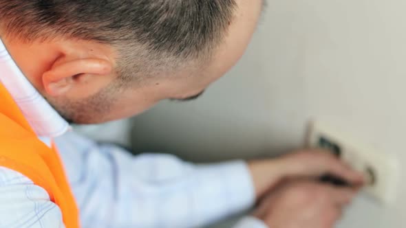 The electrician is installing the sockets in the apartment. alt