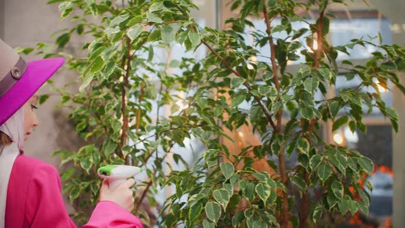 Young Girl Holding Spray Bottle and Watering Green Plants alt