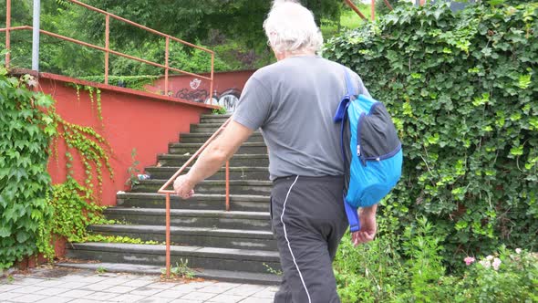 Senior athletic man with backpack climbing stairs alt
