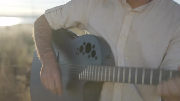 Hispanic Man Playing Guitar and Singing Against Sun Light Outdoors alt