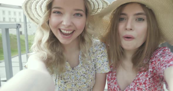 Two young beautiful smiling hipster girls in trendy summer sundress posing outdoors alt