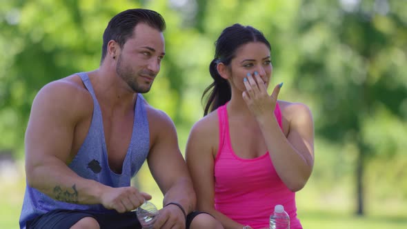 Athletic couple at park take a water break