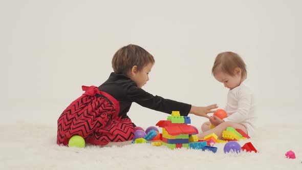 Toddler Girl Wearing Diaper and Her Sister Playing with Balls alt