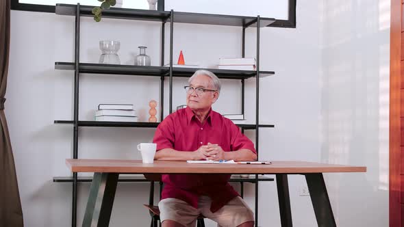 Senior Asian man sitting over office desk relaxing. alt