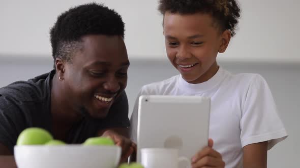 Dad and Son Laughing When Looking at Tablet Screen Spbi alt