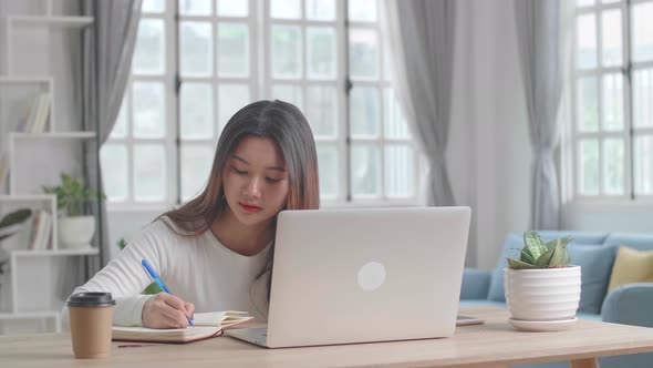 Working From Home, Asian Girl Using Laptop Computer And Writing On Notebook alt