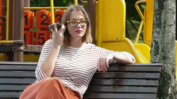 Cute Woman Using Voice Command Recorder on Smartphone at City Playground Outdoor