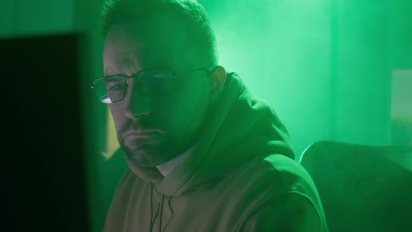 A Caucasian Man in Glasses Works on the Computer Types Checks the Information Coding Studying alt