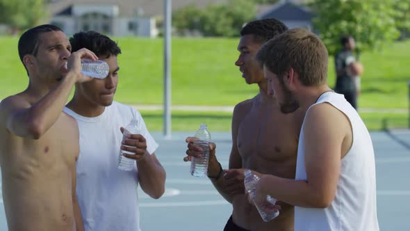 Group of teen basketball players taking water break