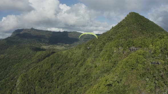 Aerial view of a person doing paragliding among the mountain, Mauritius. alt