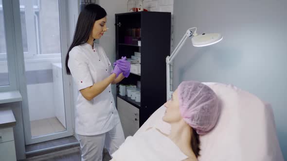 An experienced cosmetologist in sterile gloves prepares Botox injections for a woman alt