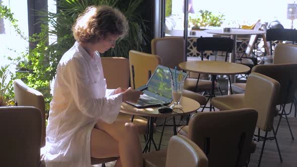 Beautiful Girl with a Laptop Working in Cafe. Business Woman Working Outdoor. Freelancing Background alt