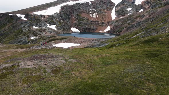 Hikers sitting at the edge of the beautiful Crater Lake near the town of Smithers in British Columbi alt