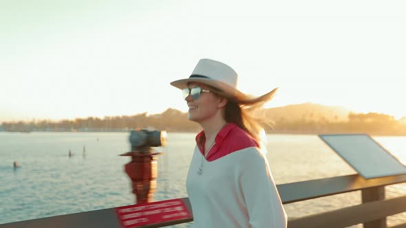 Happy Attractive Woman Walking By Pier, Enjoying Summer Sunset with Water View alt