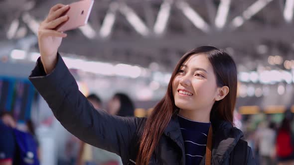 Pretty young traveller female using smartphone selfie at airport terminal
