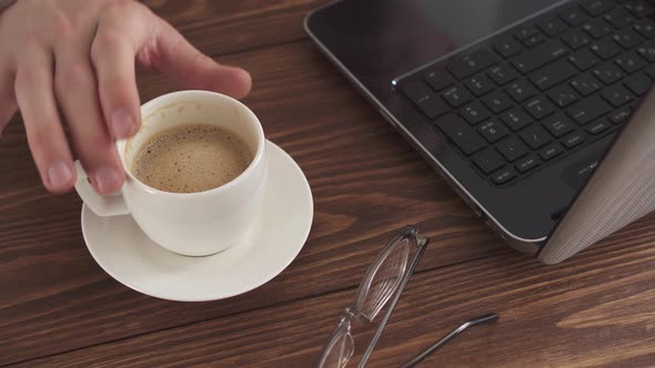 A Man Works At Home Using A Laptop Computer On A Wooden Table. Portrait Of A Business Man Working  alt