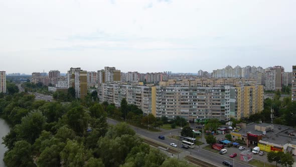 Aerial view over a river, traffic on a street and old apartment buildings, in Troieshchyna a soviet alt