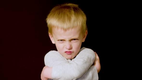 Motion studio portrait of a grumpy little boy upset that he isn't getting his way.  He crosses his a alt