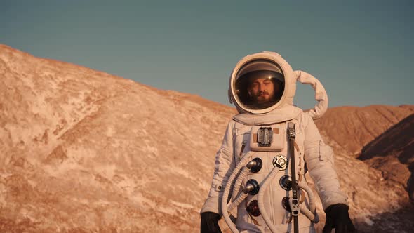 the Astronaut at the Hills Raises His Hand Up Closing From the Bright Sun alt