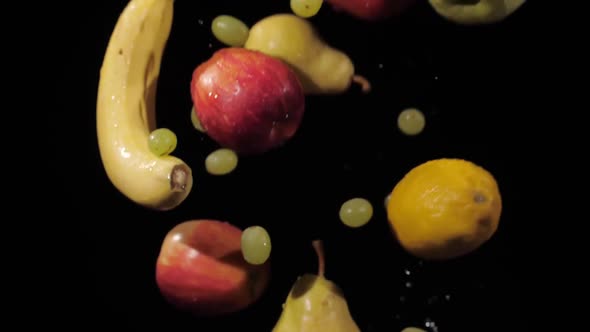 Close Up on the Fresh Grapes Apples Bananas Lemon and Pears Tossed Up and Spinning on a Black alt