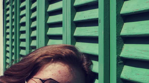 Young Sad Girl With Mask Near The Green Window Blind