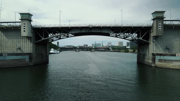 Flight Drones Across a Large Bridge Which is Located in the City on the Banks of the River alt