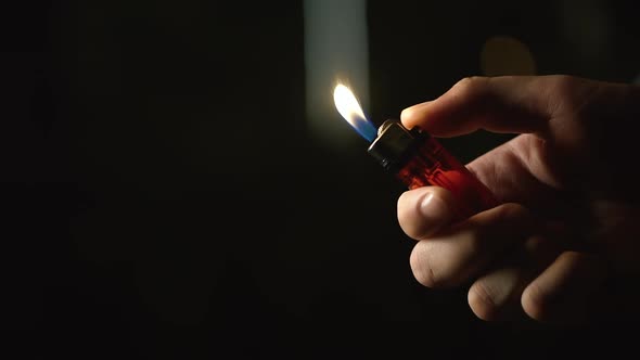 Close Up Shot of Man Hand Using Fire of Lighter Against Black Background