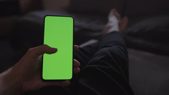 POV Man Using Phone with Green Screen Lying on a Couch