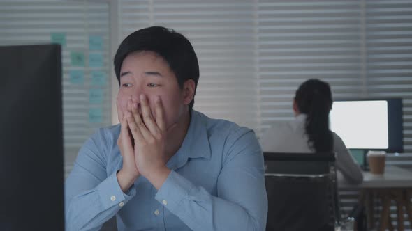 Tired Asian Male Worker Working on desktop computer in the Corporate Office, Work until night