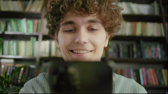 Portrait of Happy Young Student Chatting By Mobile Phone in University Library alt