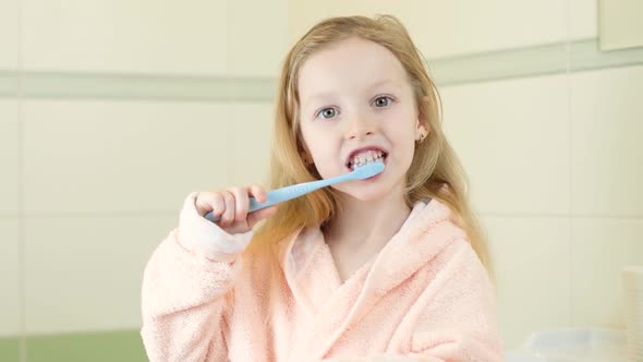 Happy Smiling Little Girl Brush Teeth Using Ultrasonic Electric Toothbrush in Bathroom at Home alt
