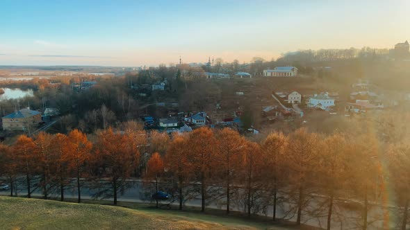 Autumn Trees are Visible in the Foreground Behind Them a Road on Which Cars Drive in the Distance a