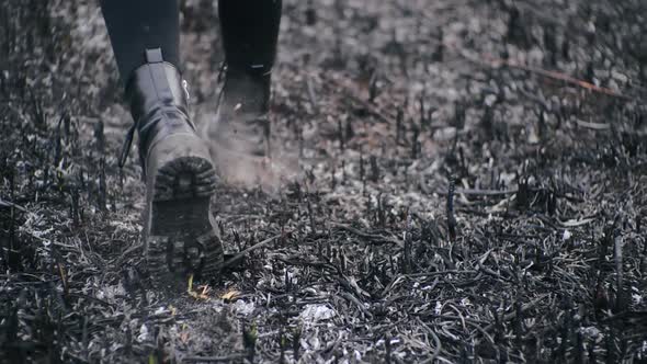 Legs of Black Stylish Boots with High Soles and Dark Leggings Walks on Burned Grass of Field After alt