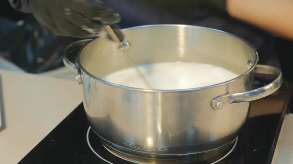 the Confectioner Very Quickly Stirs the Milk with a Whisk in a Saucepan on a Hot Stove Without alt