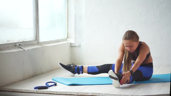 Young Woman Is Engaged in Leg-stitching After Active Physical Training alt