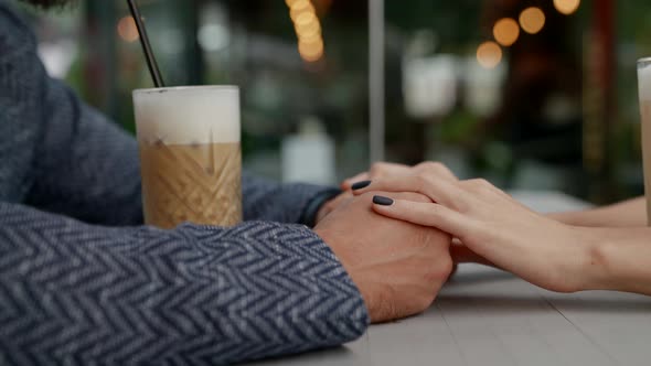 a Couple is Sitting at a Table in an Outdoor Cafe with Cocktails alt