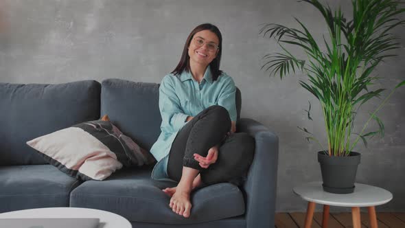 A Young Woman is Sitting on the Sofa Looking at the Camera