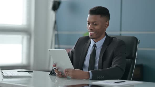 African Businessman making Video Call on Tablet in Office alt