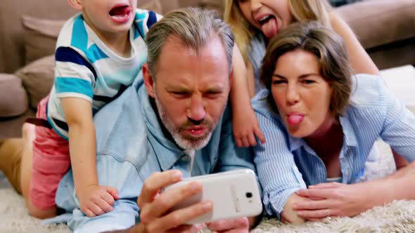 Happy family in lying on rug and talking a selfie on mobile phone alt
