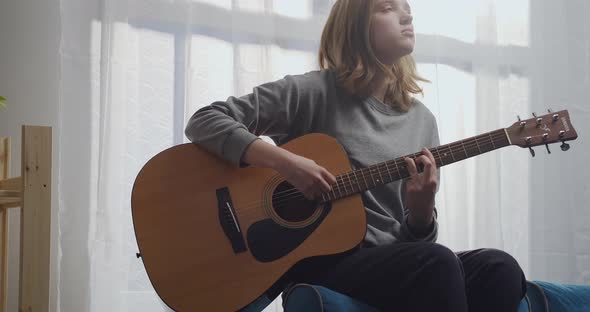 A Young Girl with Blonde Hair Is Enjoying Her Melody on an Acoustic Guitar with Beautiful Sunlight alt