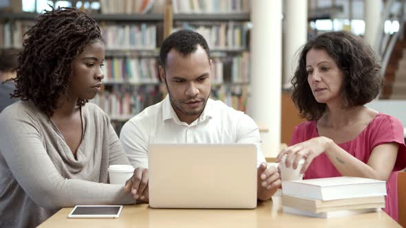 Serious Mature Students Working with Laptop at Public Library alt