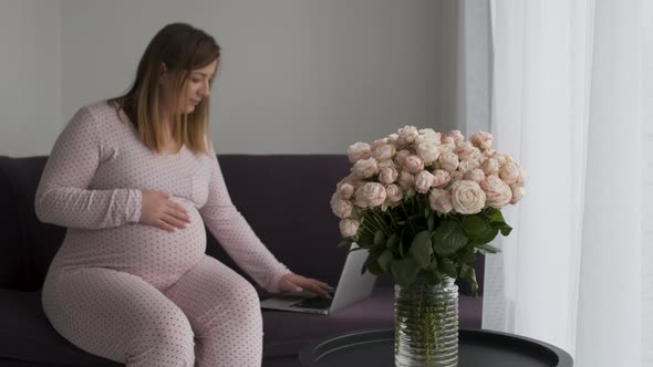 Blurred Pregnant Woman on Maternity Leave Freelancer Working By Laptop on the Sofa at Home Bouquet