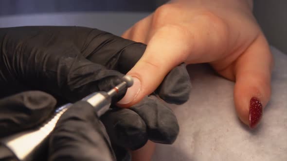 The Manicurist in the Gloves Is Working on the Nail with the Polishing Machine alt