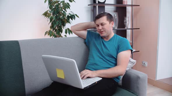 Relaxed man with laptop lies on the couch.