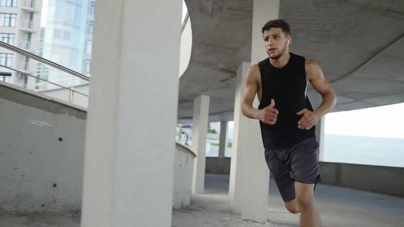 Athlete Runs Around By Levels of an Empty Parking Garage Side View alt