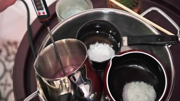 Hand made candles production, female hand mixing melting wax in pots. Slow motion alt