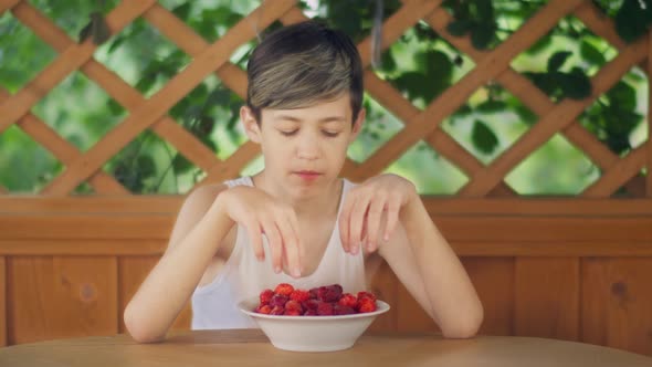 Boy Sitting in the Gazebo Outdoors and Eating Strawberries